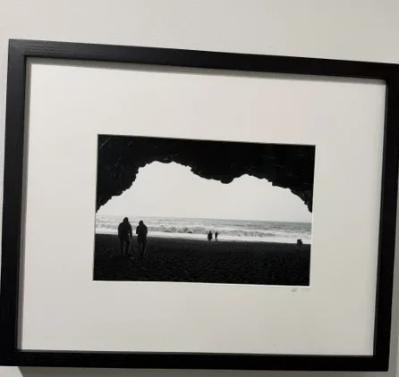 Leaving Plato's Cave by Mariana de la Vega, a black-and-white photograph of figures silhouetted at the mouth of a sea cave.