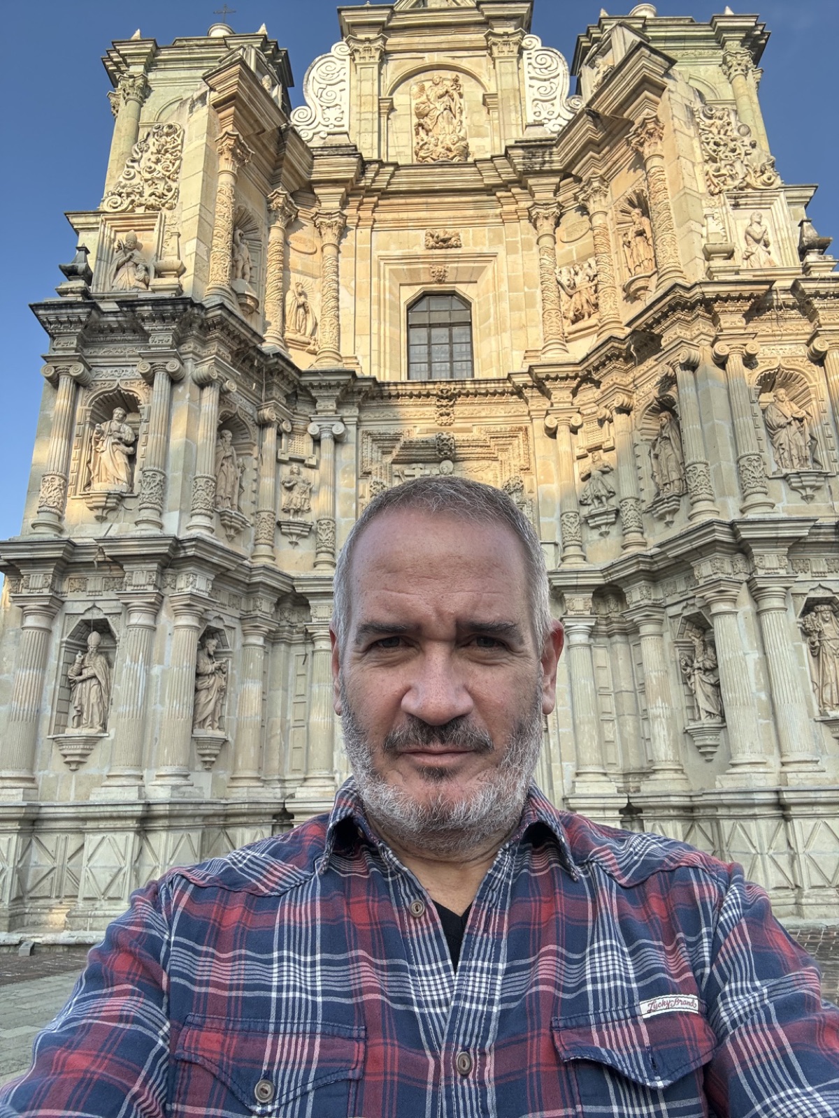 Portrait of Tomás Juan Urrutia Sodi in front of a historic church facade.