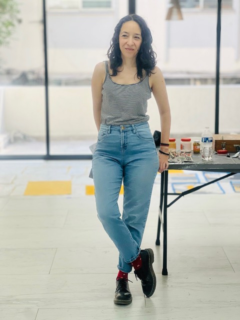 Portrait of Verónica Rodríguez standing in a studio setting beside a table.